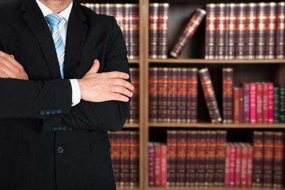Anwalt steht vor Regal mit Gesetzbüchern